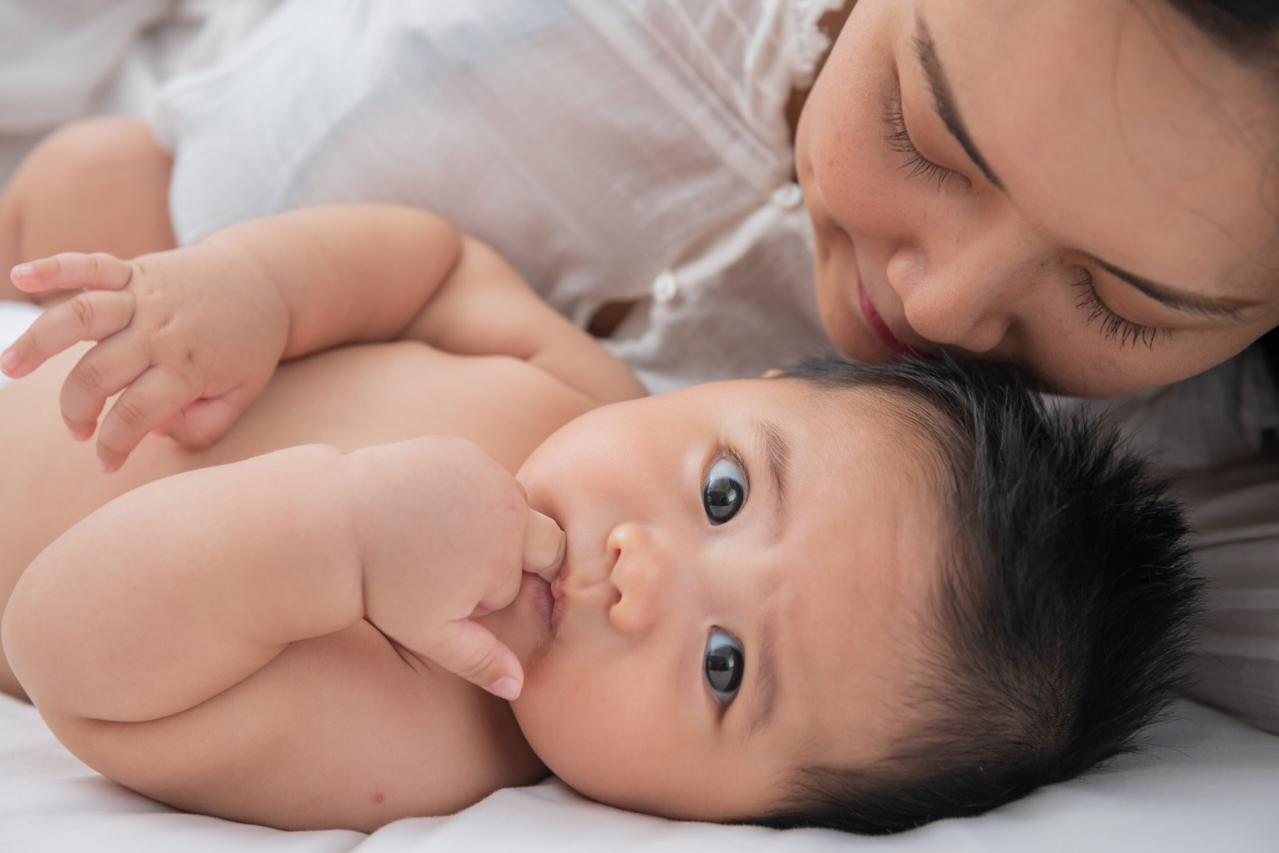 Loving mom carying of her newborn baby at home. Bright portrait of happy mum holding sleeping infant child on hands. Mother hugging her little 6 months old son. Family in the house. Lifestyle.